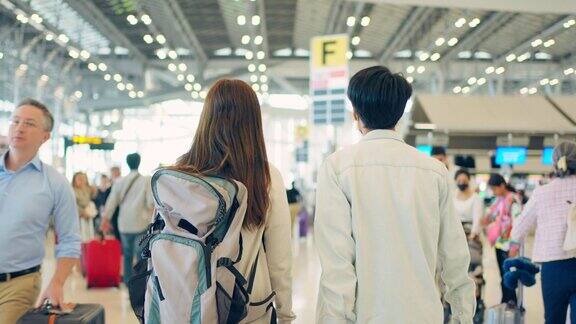亚洲年轻情侣乘客戴着口罩走在机场候机楼迷人美丽的女游客朋友心情愉快兴奋地乘飞机出国旅游度假旅行