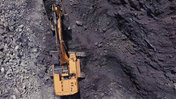 在露天采煤区黄色煤矿挖掘机将煤炭装入大型自卸卡车采石场采煤过程的航拍镜头