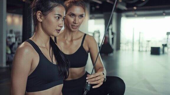 年轻的亚洲女性在健身房里锻炼在私人教练的指导下锻炼肌肉和力量健身在健身房锻炼