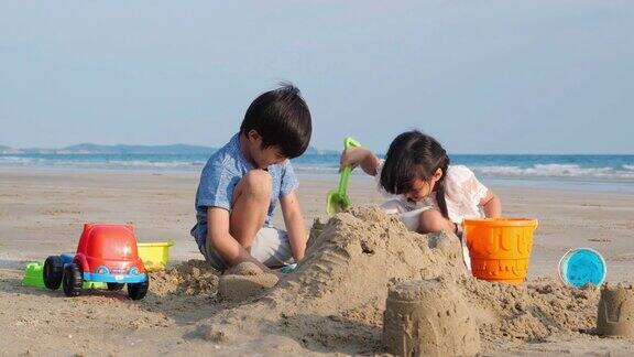 亚洲小孩弟弟和妹妹一起在海滩上玩堆沙夏天在度假家庭、旅行和关系4k决议