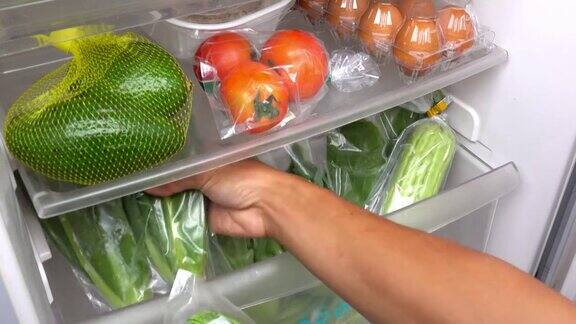 一个男人正在把蔬菜放进冰箱