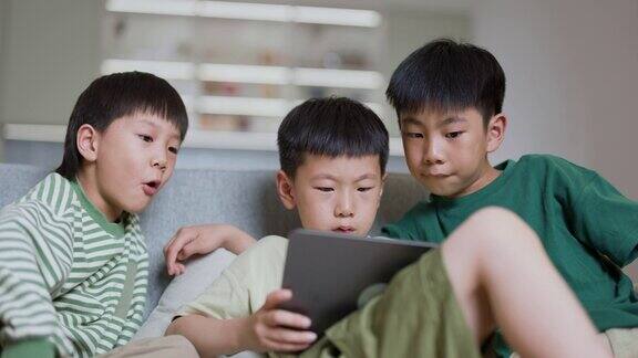 三个男孩在家里使用数字平板电脑进行在线学习