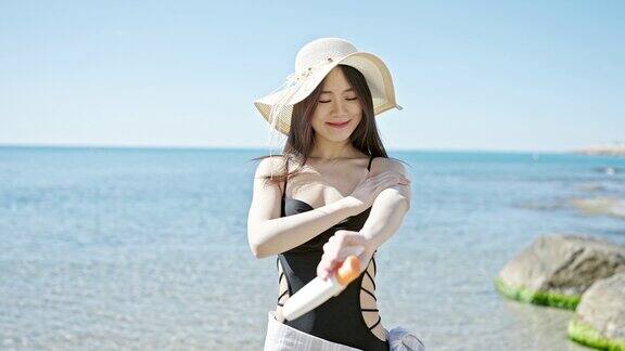 年轻的中国女游客微笑着自信地在海边涂防晒霜