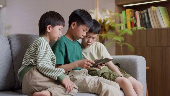 三个亚洲男孩在客厅用平板电脑玩游戏