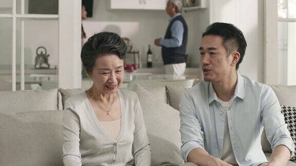 年长的亚洲母亲和成年的儿子在家里聊天