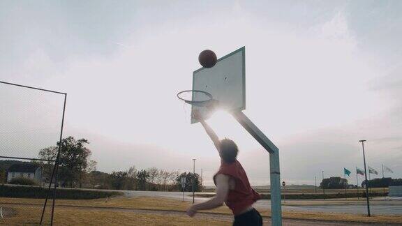 MSYoungman打篮球在阳光明媚的户外篮球场上