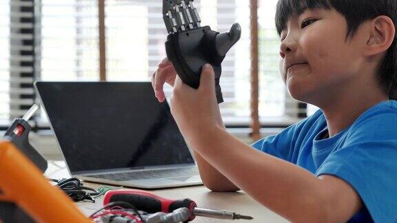 男孩在家里用电脑制作和编程并制作一个机器人手臂作为学校的科学项目他对自己的工作非常满意教育、儿童、技术、科学是人们的理念