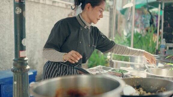 亚洲女厨师烹饪美味的传统泰式炒面在曼谷街头市场厨房-泰国街头食品
