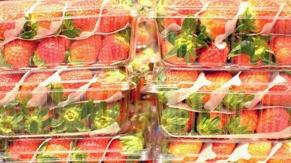 超市里成堆的新鲜草莓装在塑料容器里