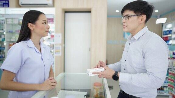 4K亚洲女药剂师在药店向男性顾客讲解药物和补品