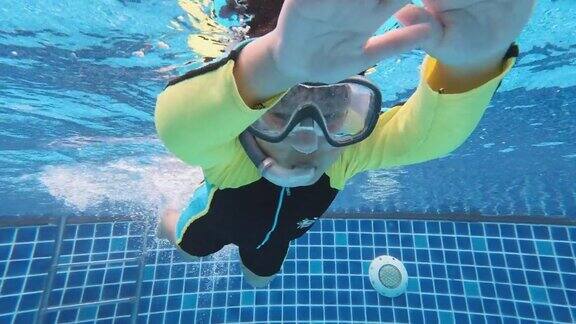 一个亚洲男孩在水下玩耍和游泳看着游泳池的摄像头