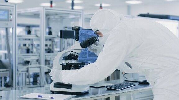 科学家穿着防护服用显微镜做研究