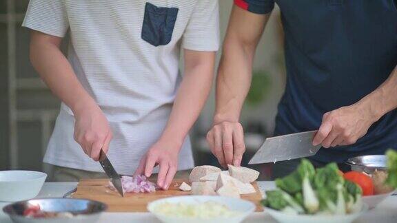 周末一对亚洲华人父子在自家后院的湿厨房里切芋头洋葱准备晚餐
