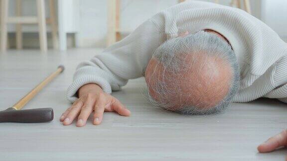 亚洲老年男性在家中与助行器行走时摔倒在地老人年迈成熟的爷爷退休后在家里的客厅独自做物理治疗后发生了事故