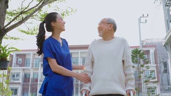 护理护士扶着年长的男性病人在户外行走