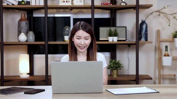 漂亮的女人在家里用笔记本电脑工作亚洲女商人在家里通过视频在线会议