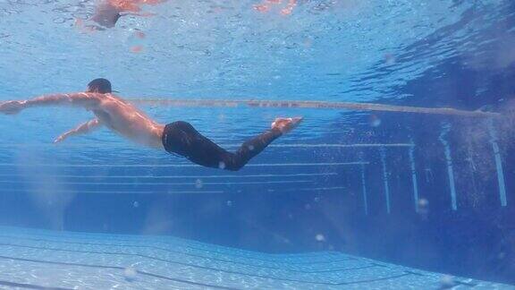 水下低角度看亚洲华人男子游泳蝶泳风格在游泳池
