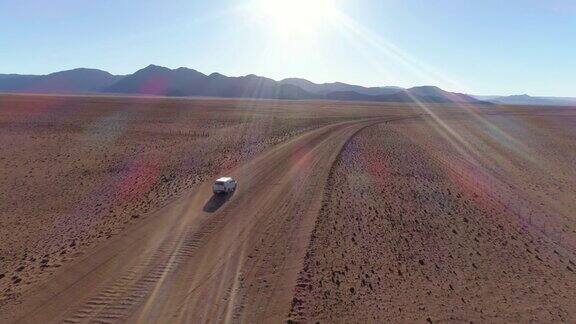 鸟瞰图的旅游车辆行驶在沙砾道路在纳米比亚的沙漠
