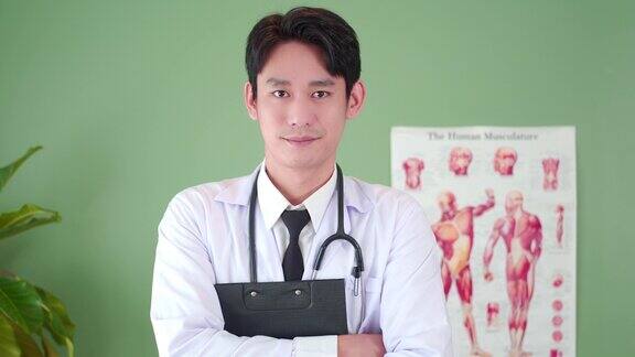 自信的亚洲年轻男性医生的肖像微笑在医院的医疗办公室专业的医生穿着白色的实验室制服拿着病历和听诊器的剪贴板