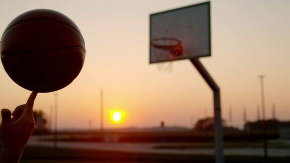 日落时分在户外篮球场上用手指旋转篮球