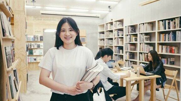 一个可爱的年轻亚洲女学生站在图书馆的肖像