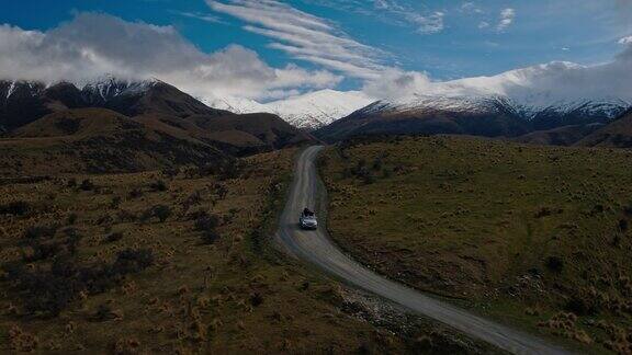 鸟瞰图SUV驾驶在沙漠向雪山山峰在新西兰