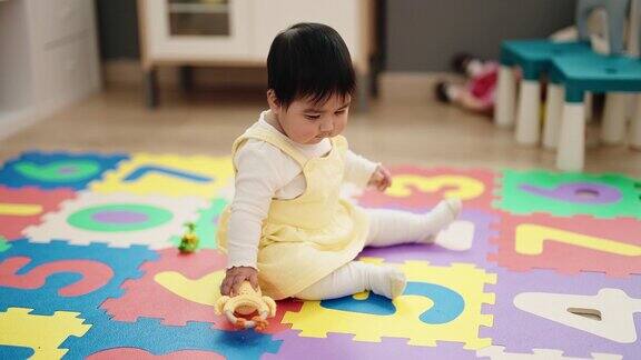 可爱的西班牙婴儿洞玩具坐在幼儿园的地板上