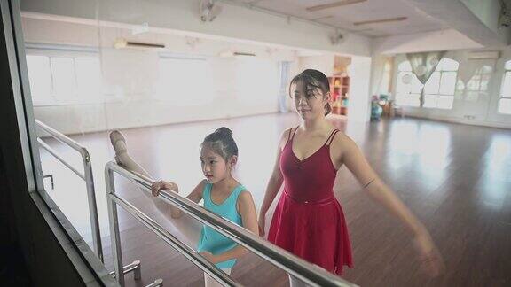 透过窗户看亚洲中国少女芭蕾舞演员训练她的年轻女学生在工作室