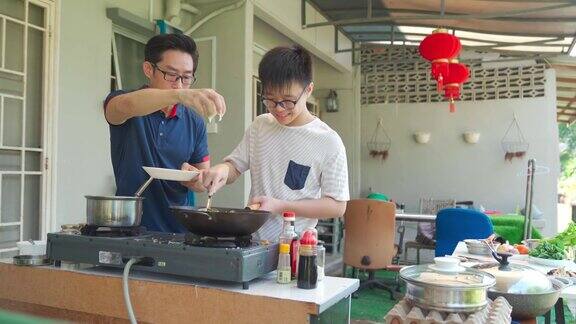 亚洲华人父亲和儿子一起在潮湿的厨房后院周末准备晚餐