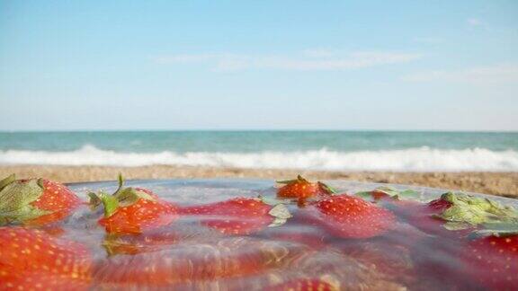 我从一盘水里拿草莓海边的海滩特写镜头