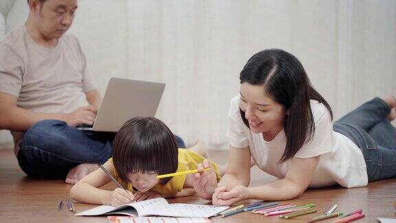 亚洲幸福家庭在客厅一起做活动妈妈教孩子画画她和孩子们一起躺在地板上家庭关系