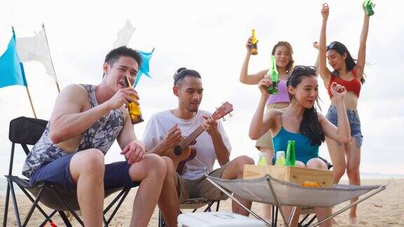 一群亚洲年轻男女在海滩上聚会吸引快乐的朋友在海边露营唱歌跳舞享受假期在热带海岛度假旅行