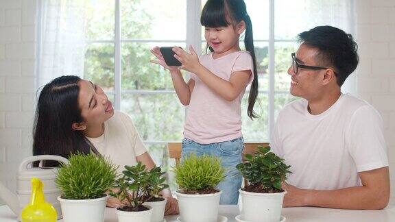 快乐快乐的亚洲家庭爸爸妈妈和女儿用智能手机在花园里的植物拍照