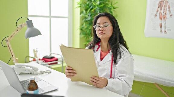 年轻的中国女医生在诊所阅读医疗报告