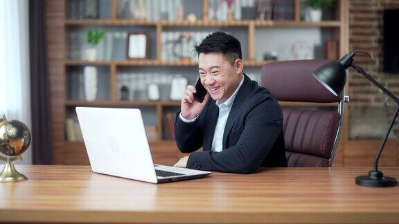 满意的亚洲商人在办公室里打电话伟大的结果快乐的经理商人