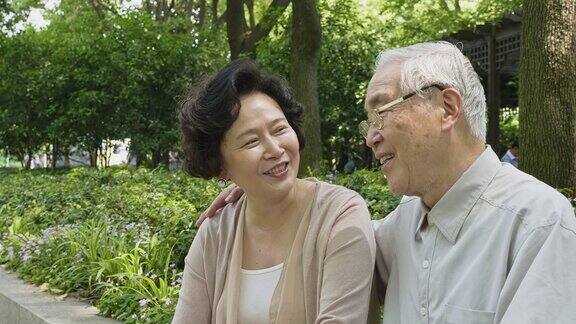 一对大笑的中国老夫妇坐在公园里