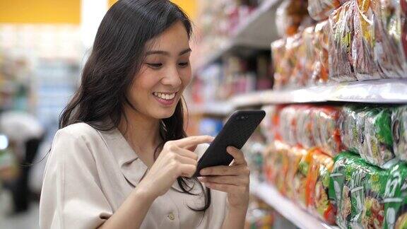 亚洲女性在超市使用智能手机