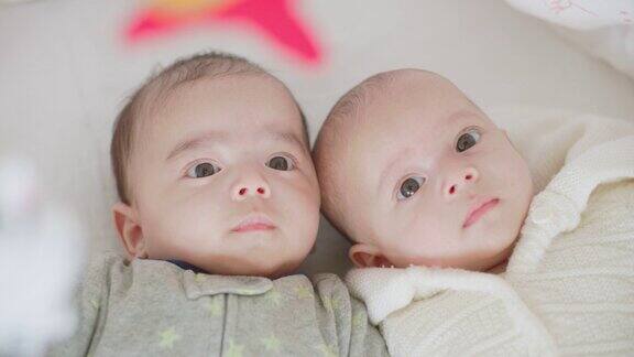 可爱的刚出生的双胞胎宝宝男孩和女孩一起躺在家里的床上