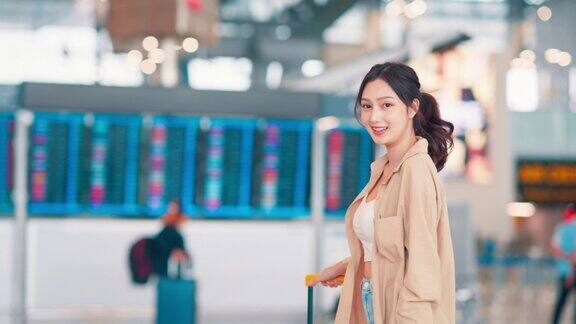 幸福微笑的亚洲女旅客走在机场候机楼行李箱行李