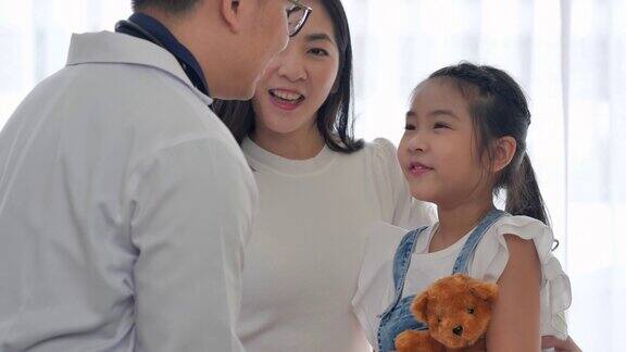 6岁亚洲小女孩坐在医院里向亚洲儿科医生男触摸双手的幸福医患会诊概念
