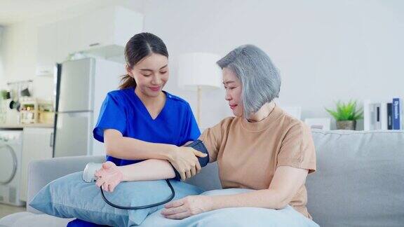 亚洲看护医生用血压计检查老年病人年轻的女治疗师护士在养老院照顾坐在沙发上的老年妇女医疗保险服务理念