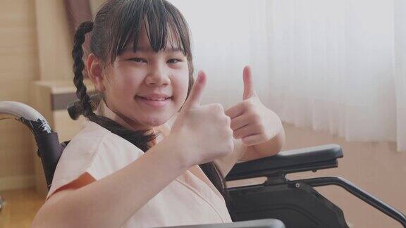 亚洲小生病女孩坐在轮椅上微笑着在医院等待医疗服务的肖像孩子感觉良好充满希望高兴地竖起大拇指