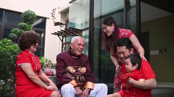 春节团圆饭后亚洲华人家庭的老爷爷给孙子送红包红包吃传统菜肴生鱼