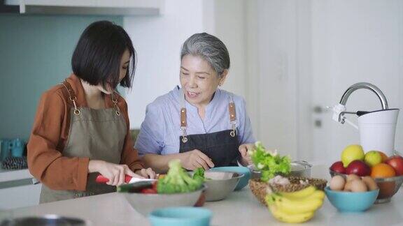 一位亚洲华人奶奶在厨房教孙女切菜
