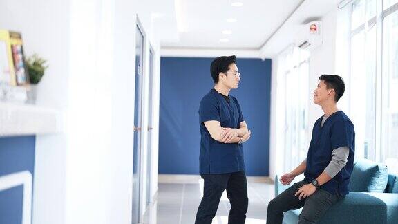 两名中国男护士在喝咖啡休息时在医院走廊聊天