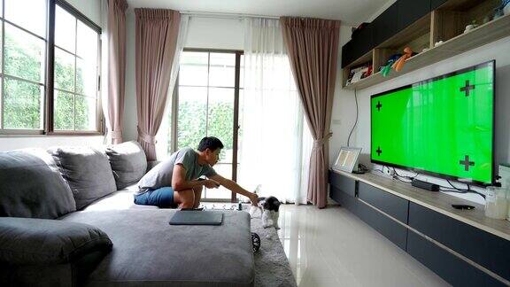男性的手在家里的绿色屏幕上用电视遥控器切换频道