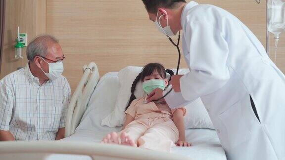 亚洲男医生带着口罩来到康复室向躺在病床上的儿童病人询问健康问题男医生检查心率、脉搏和提供健康保健咨询