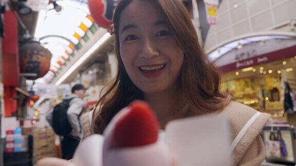 一名亚洲女子正在日本大阪的黑门市场观光享受当地的美食