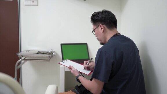 亚裔华人中年男性医生在笔记本电脑上查看病人记录