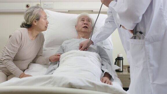 年轻的亚洲医生在医院病房检查老年病人